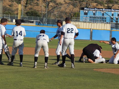 Outfielder Jack Rosenberg, on the ground, is hugged by Dalton Duarte, as other Raiders players line up to congratulate him for hitting a walkoff home run in the 14th inning in Tuesday's season finale.