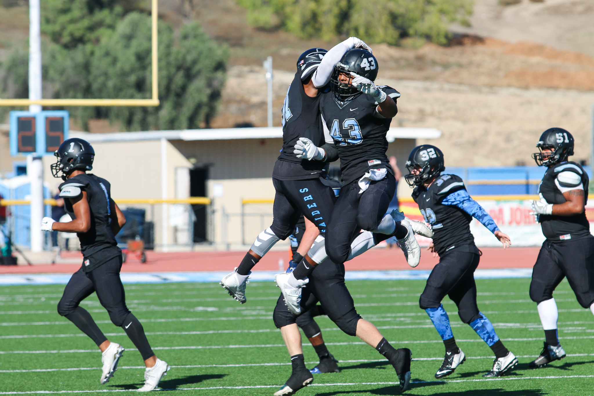 Raider defensive lineman Jordan Flack (aerial, right), celebrates a defensive stop during Moorpark College's 35-28 victory over Cerritos College.